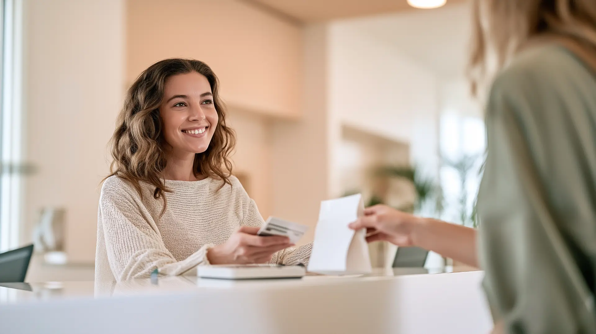 Patient paying by card at a clinic reception desk while staff hands over a bag of wellness products, representing cash-pay purchases